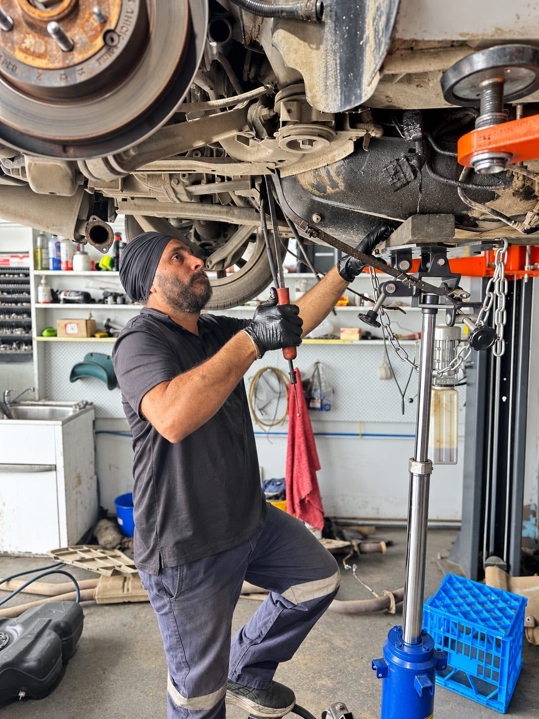 Mechanic repairing suspension components under a car on the hoist
